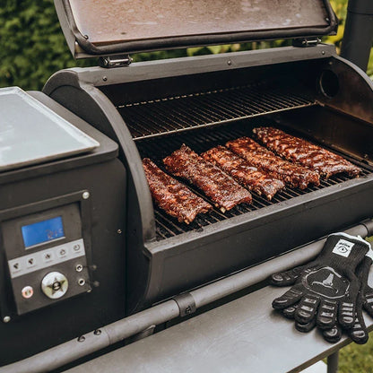 Barbecue à pellets MOESTA Sheriff ouvert avec travers de porc en cuisson sur grille et écran de contrôle numérique visible.